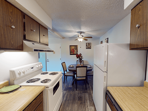A kitchen with a stove, table and chairs.