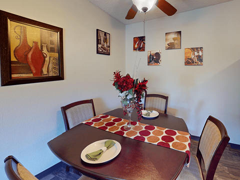 A brown table with a plate and a vase of flowers on it.
