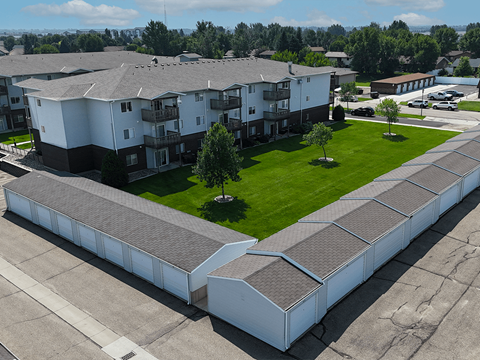 Apartment complex with a long white building and a green lawn.