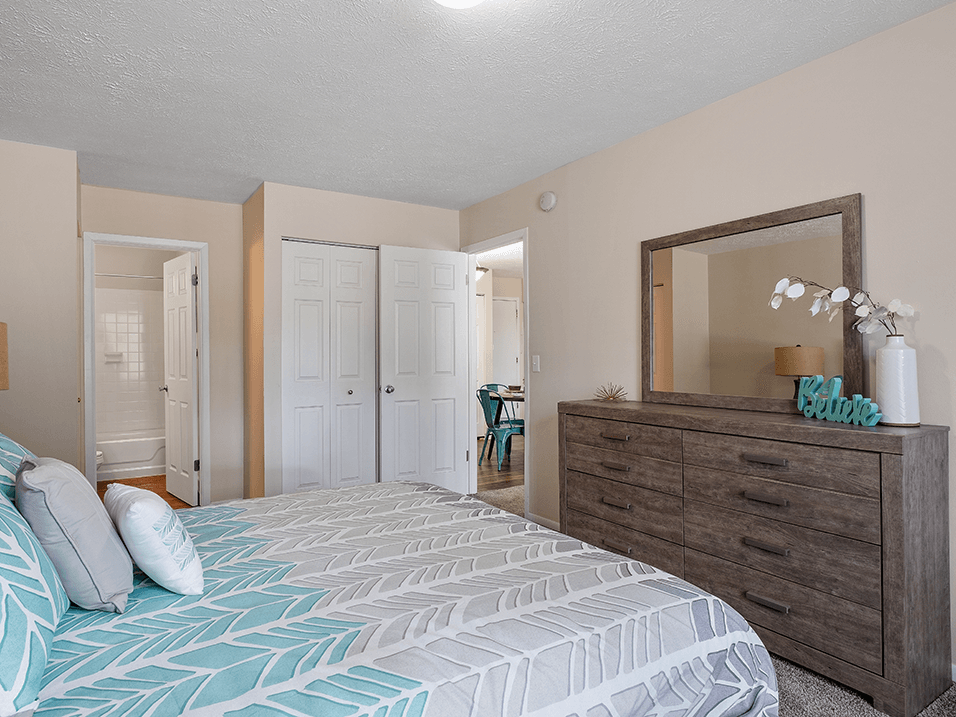 a bedroom with a large bed and a dresser with a mirror