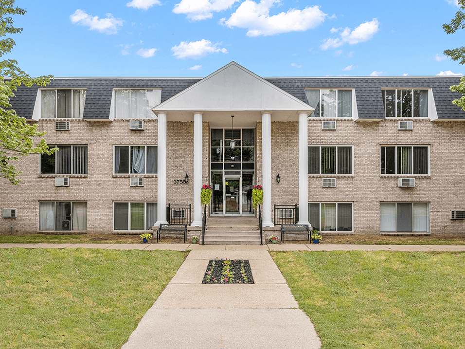 a brick building with white pillars and a gray roof