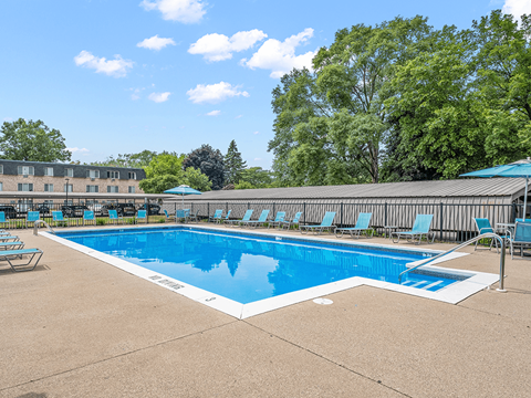 a swimming pool with chaise lounge chairs and trees in the background