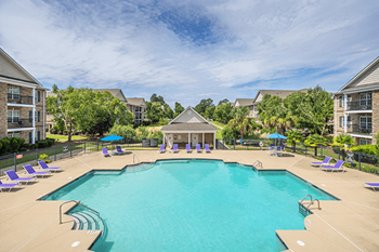 A large swimming pool surrounded by purple lounge chairs and umbrellas.