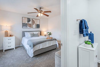 A bedroom with a bed, nightstand, and a ceiling fan.