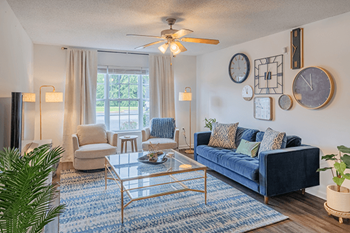 A living room with a blue couch and a glass coffee table.