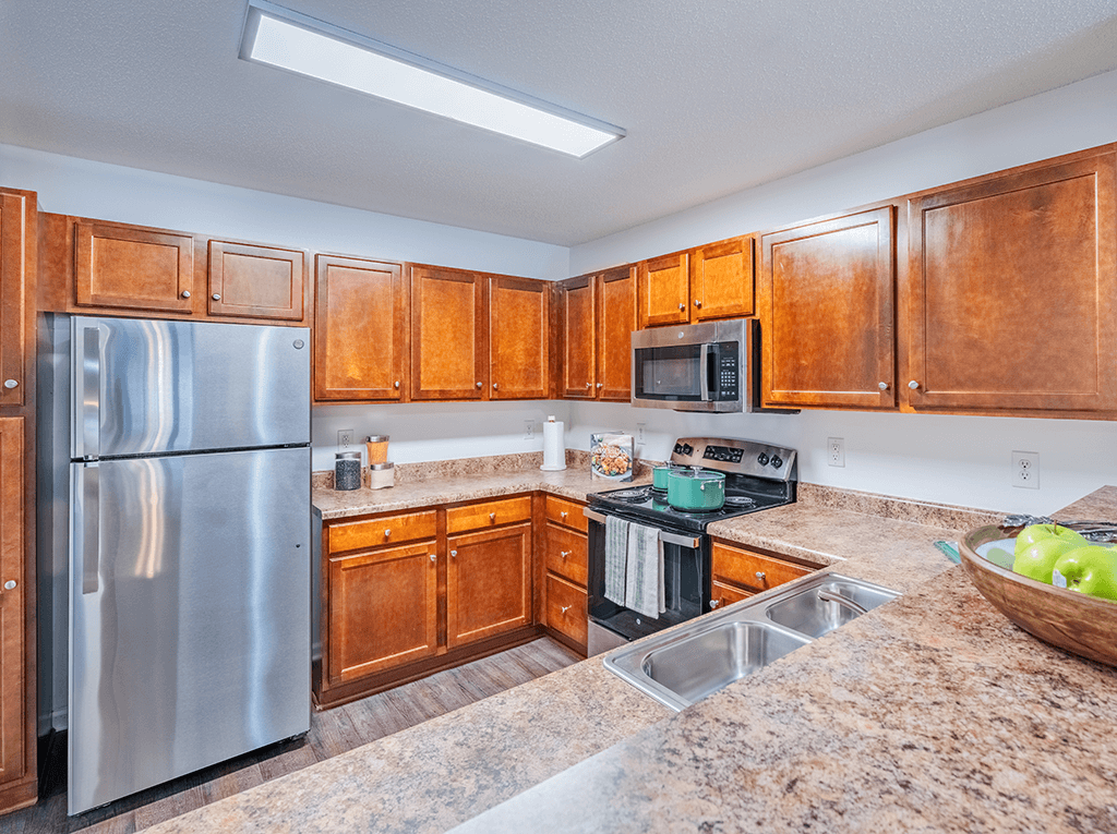 A kitchen with wooden cabinets and a stainless steel refrigerator.
