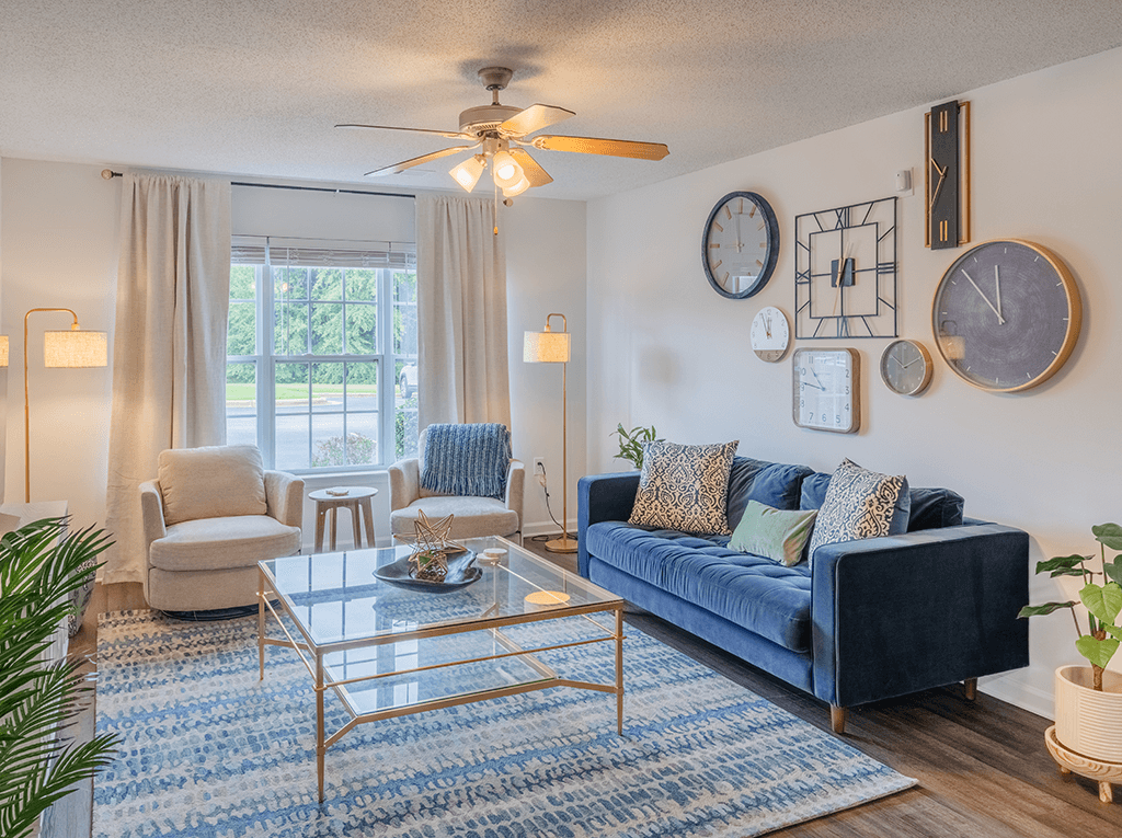 A living room with a blue couch and a glass coffee table.