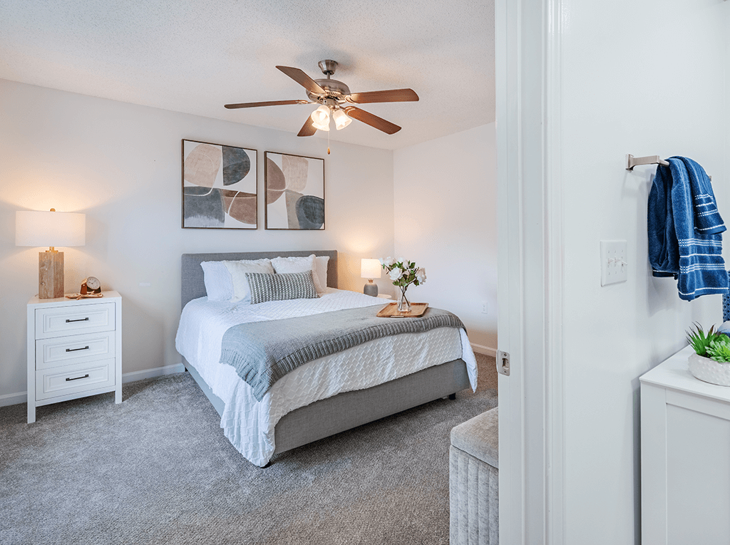 A bedroom with a bed, nightstand, and a ceiling fan.