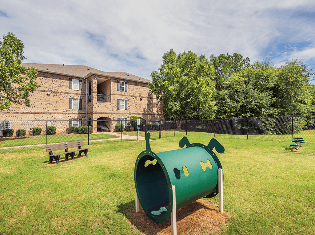 A playground with a green slide and a building in the background.