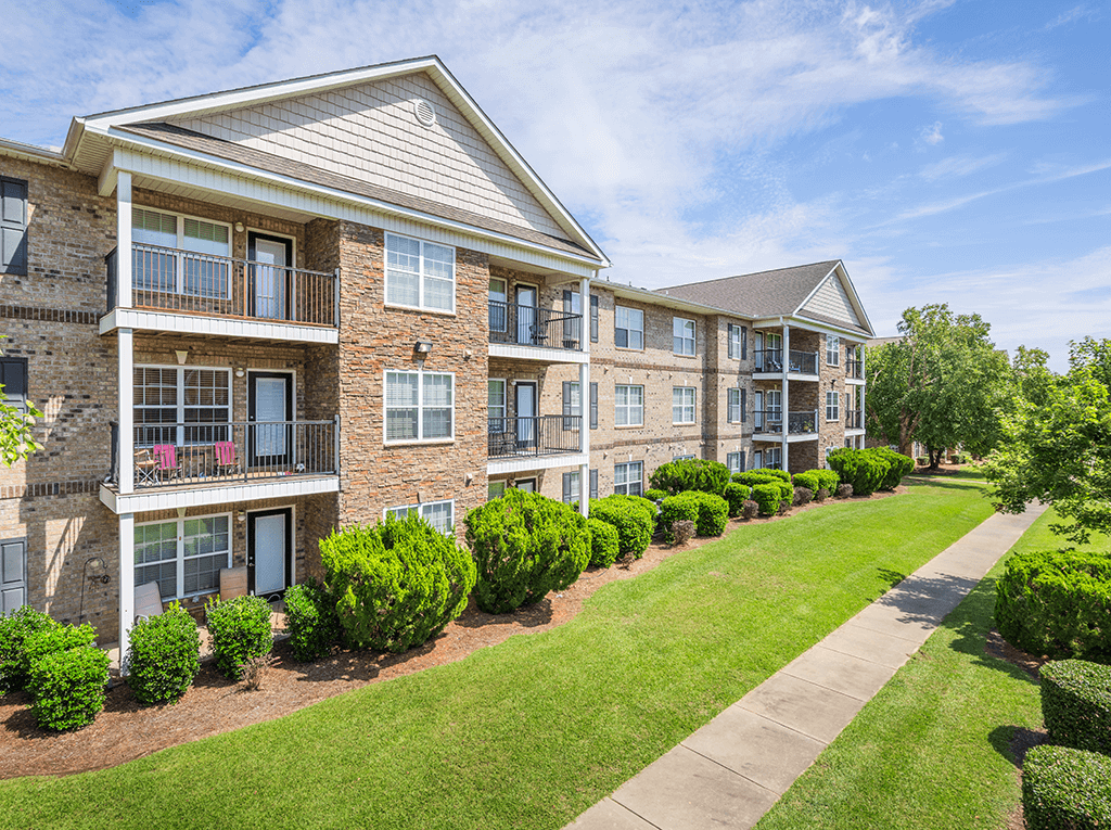 A row of apartment buildings with green bushes in front.