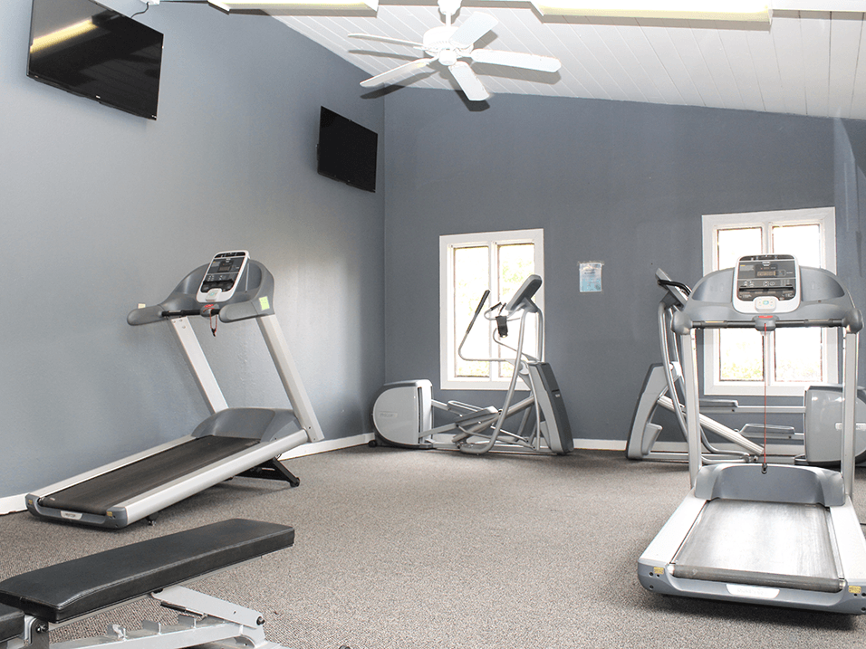 a gym with exercise machines and a ceiling fan