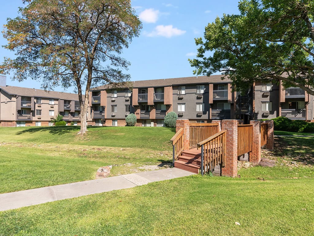 A tree stands in front of apartment buildings.