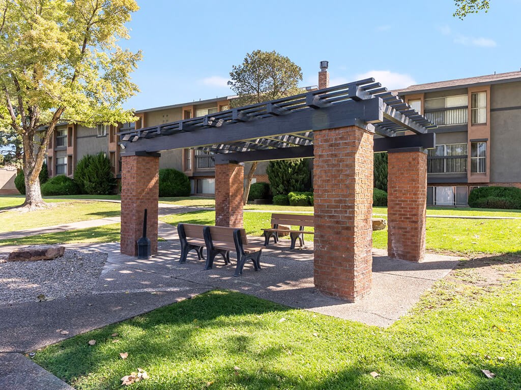 A brick structure with a roof and benches in front of a building.
