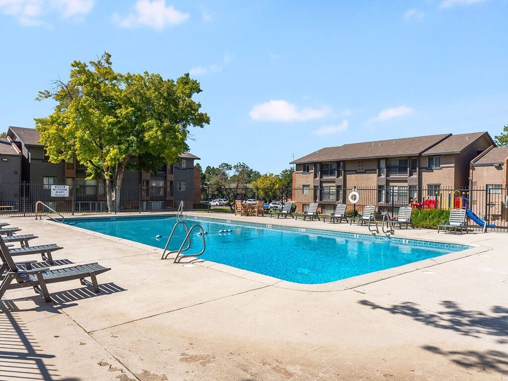 A swimming pool surrounded by a concrete floor and a tree.