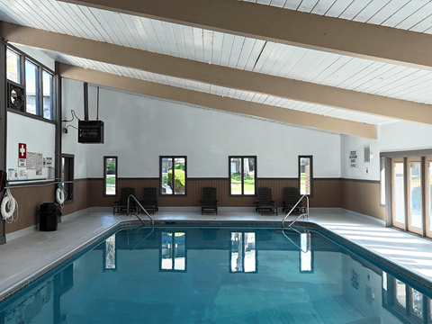 A large indoor swimming pool with lane dividers and a few chairs.