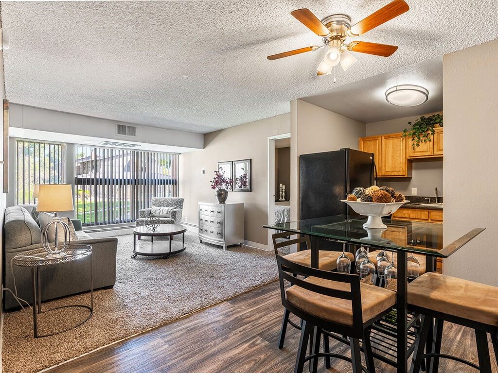A well-lit living room with a glass dining table and chairs.
