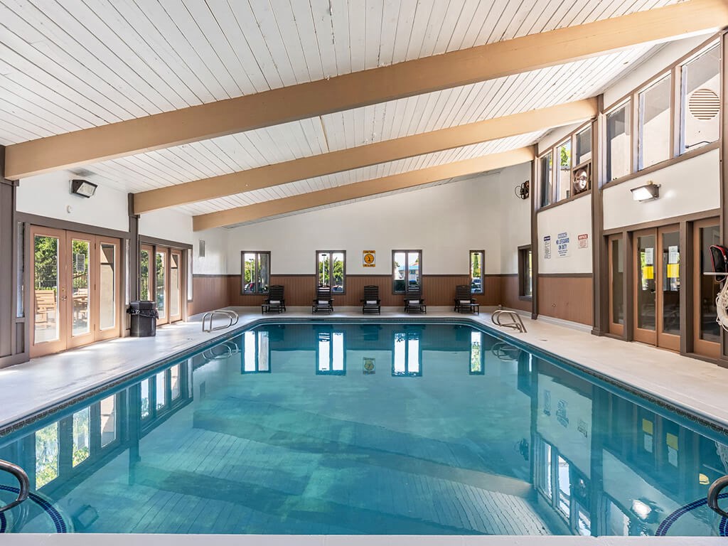 A large indoor swimming pool with a wooden ceiling and glass walls.