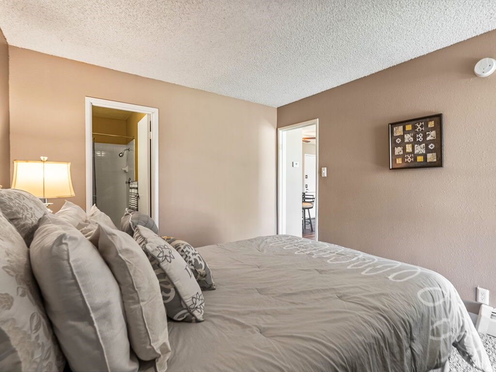 A bedroom with a large bed and a lamp on the side table.