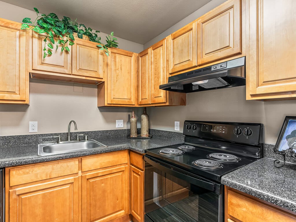 A kitchen with wooden cabinets and a black stove top oven.