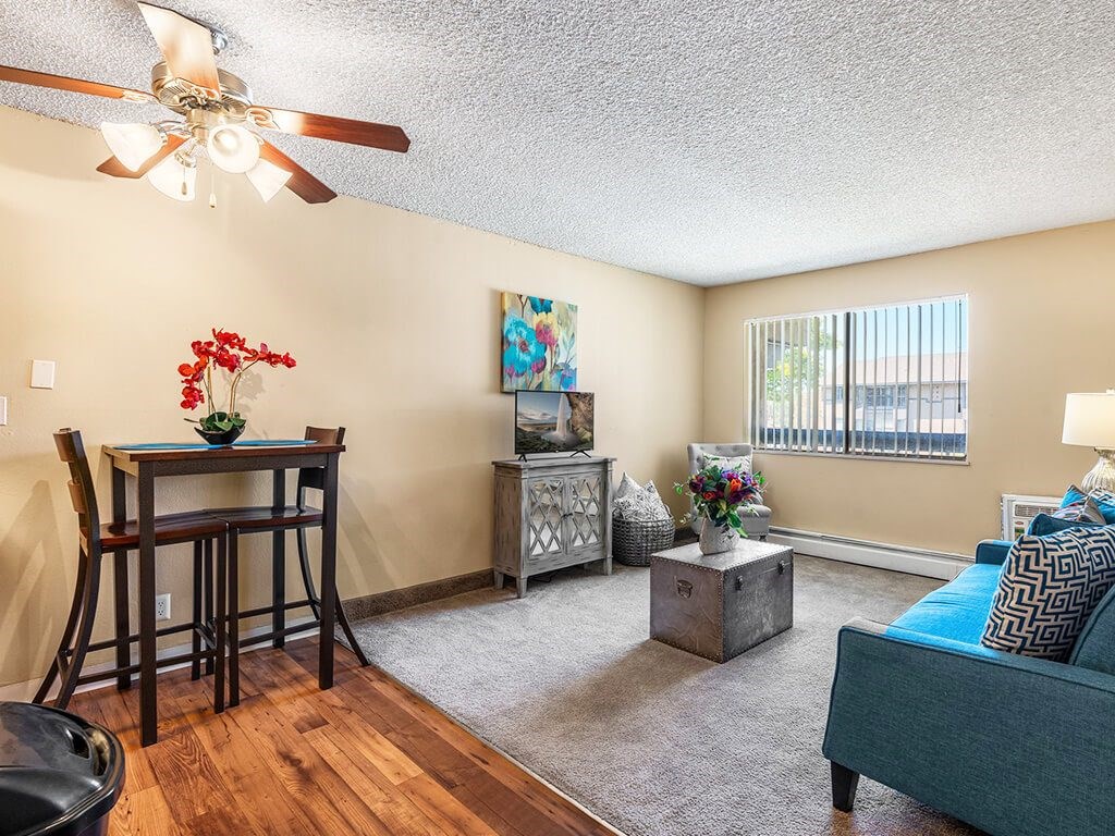 A living room with a blue couch and a wooden dining table.