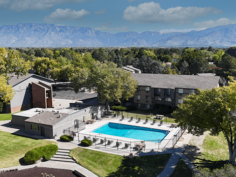 A large building with a pool in the foreground and mountains in the background.