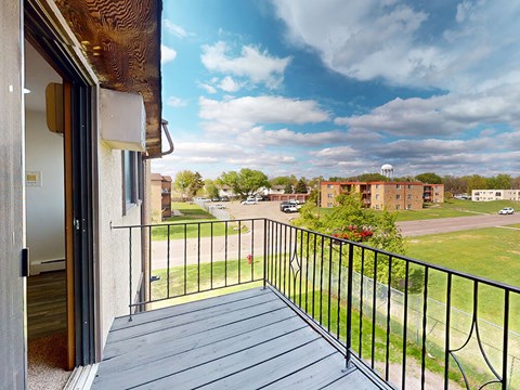A balcony with a view of a parking lot and buildings.