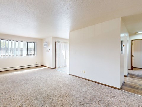 A spacious room with a carpeted floor and a sliding glass door.