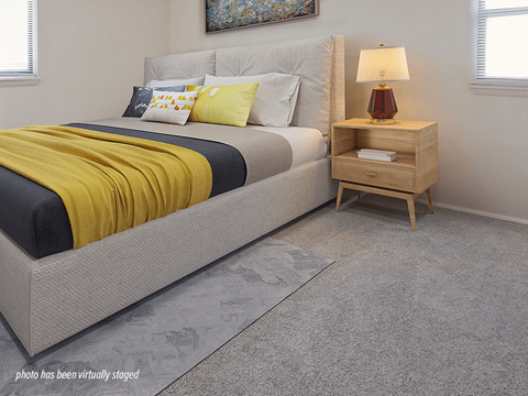A bedroom with a bed, nightstand, and lamp.