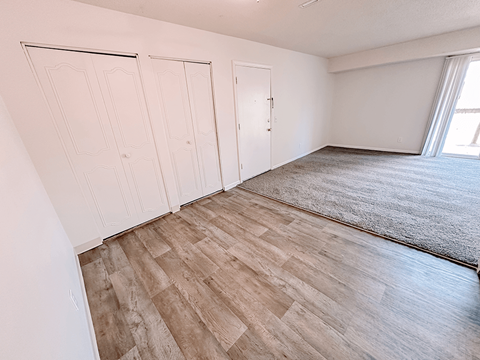 the living room and bedroom of an apartment with wood flooring