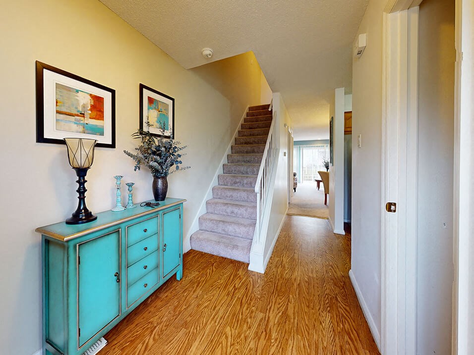 a living room with stairs and a blue dresser