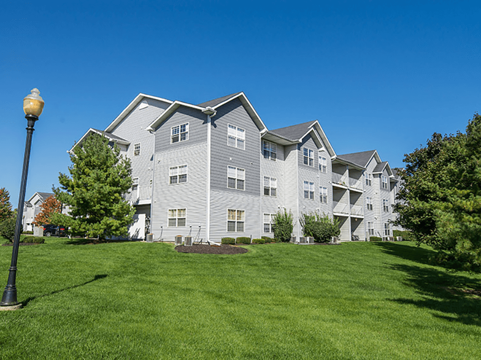 a large gray apartment building on a green lawn