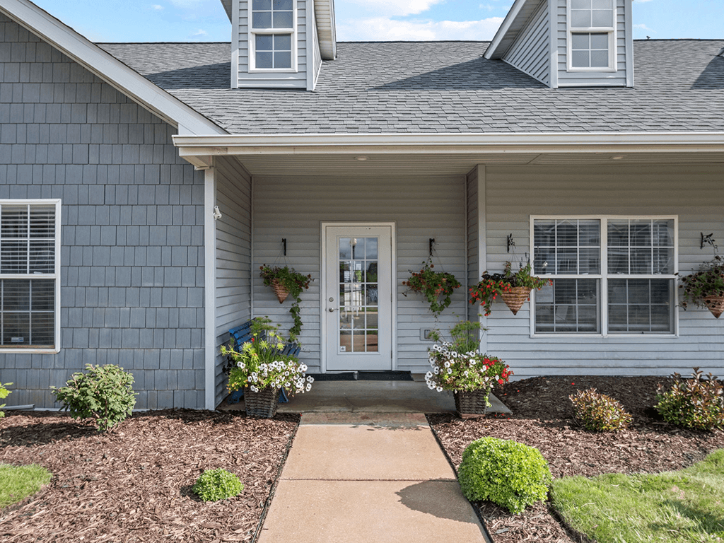 the front of a house with a walkway and plants