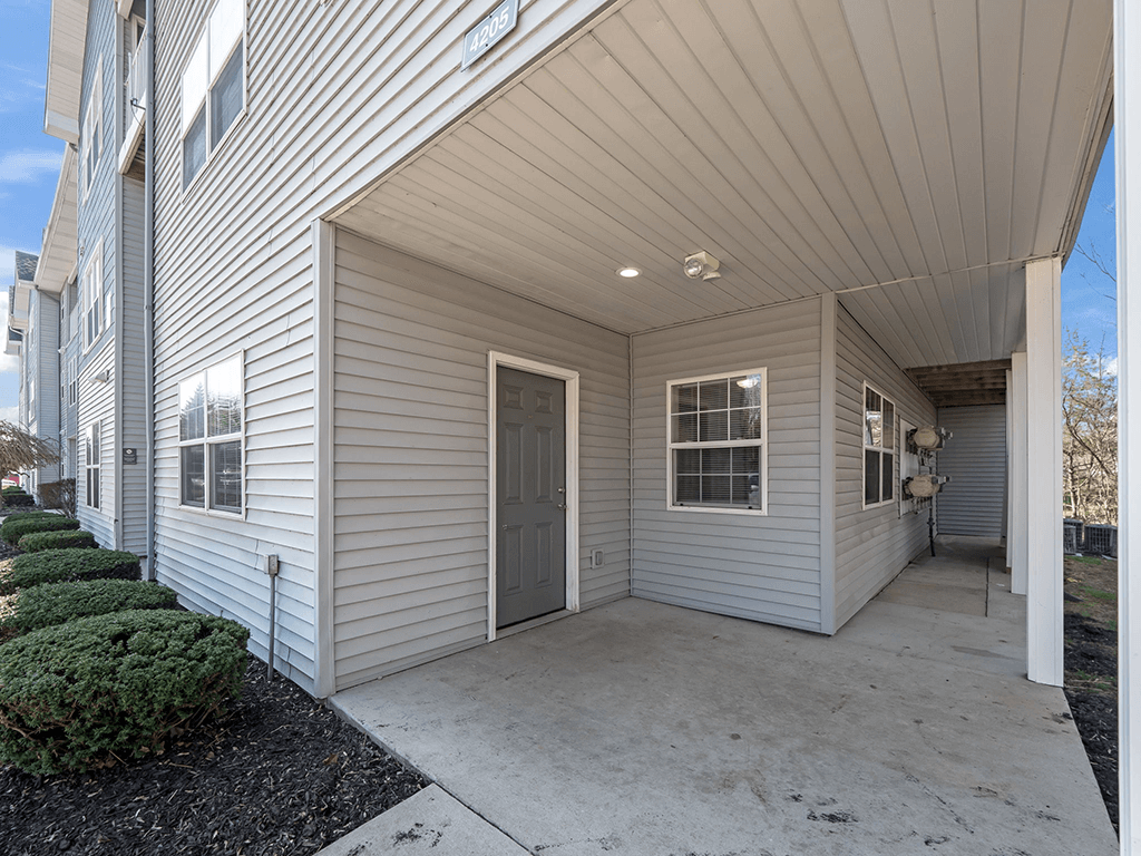 the front door of a white house with a concrete porch