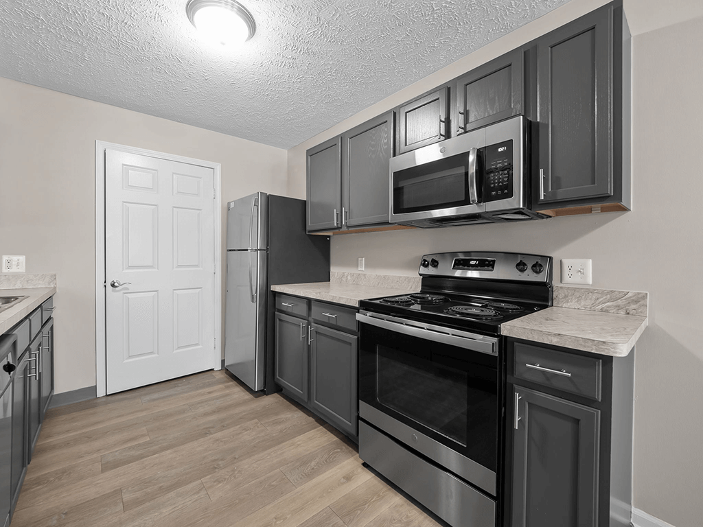 a kitchen with black cabinets and stainless steel appliances and a refrigerator