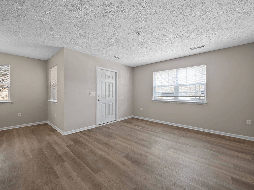 an empty living room with a white door and a window