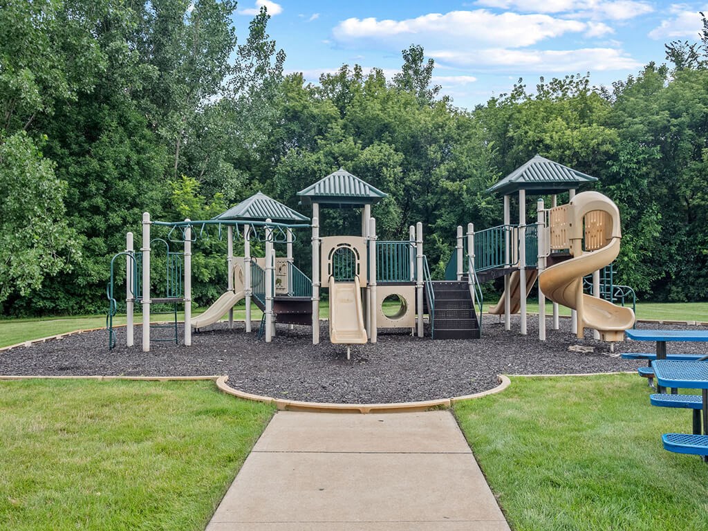 a playground with a swing set and slides in a park