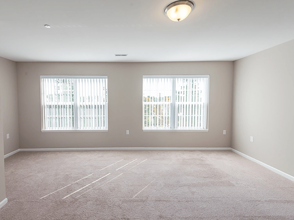 an empty room with three windows and a carpeted floor