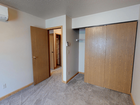 A room with a carpeted floor and two wooden doors.