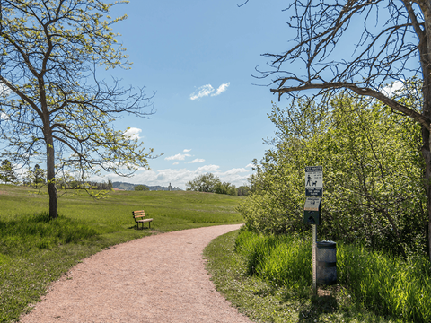 A path in a park with a sign on the right.