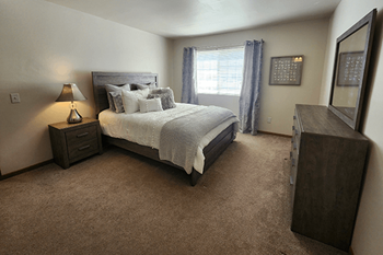 A bedroom with a large bed and a nightstand with a lamp.