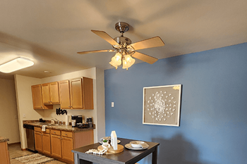 A kitchen with a ceiling fan and a table with food on it.