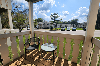 A balcony with a chair and table overlooking a street.