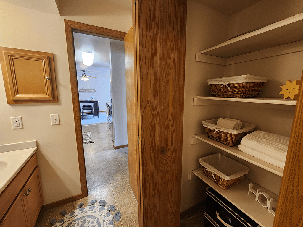 A kitchen with a pantry door open to a living room.