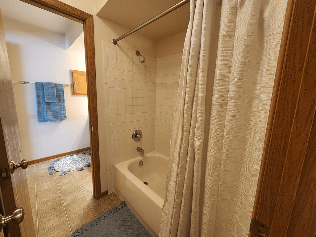 A bathroom with a white tub and a white shower curtain.