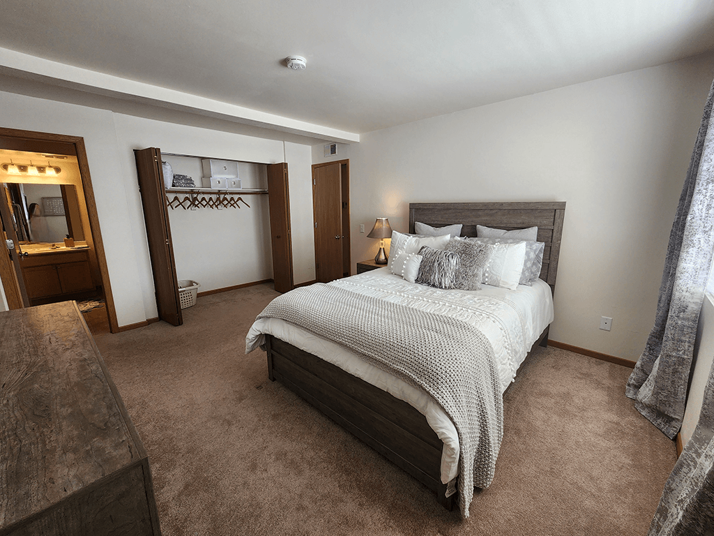 A bedroom with a large bed and a wooden headboard.