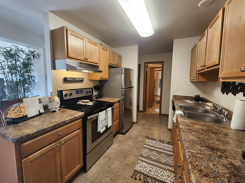 A kitchen with brown cabinets and a granite counter top.