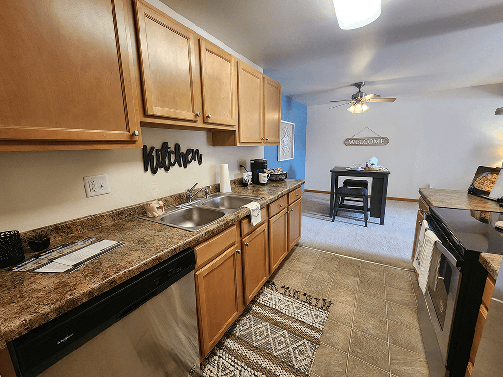 A kitchen with wooden cabinets and a stainless steel dishwasher.