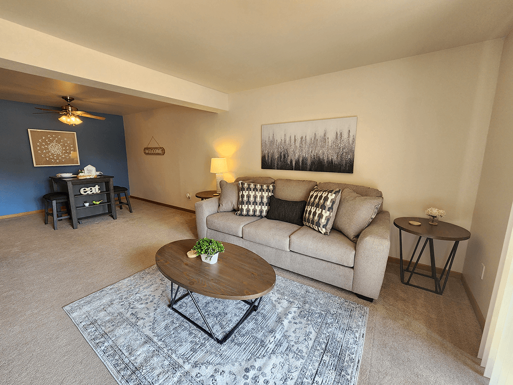 A living room with a couch, coffee table, and a painting on the wall.