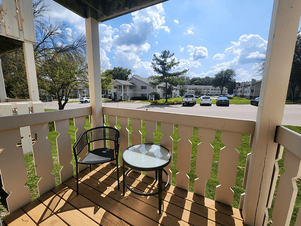 A balcony with a chair and table overlooking a street.