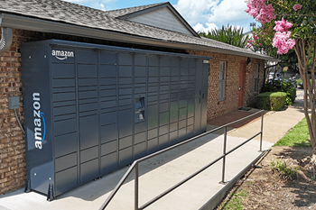 A large Amazon storage unit is located outside a brick building.